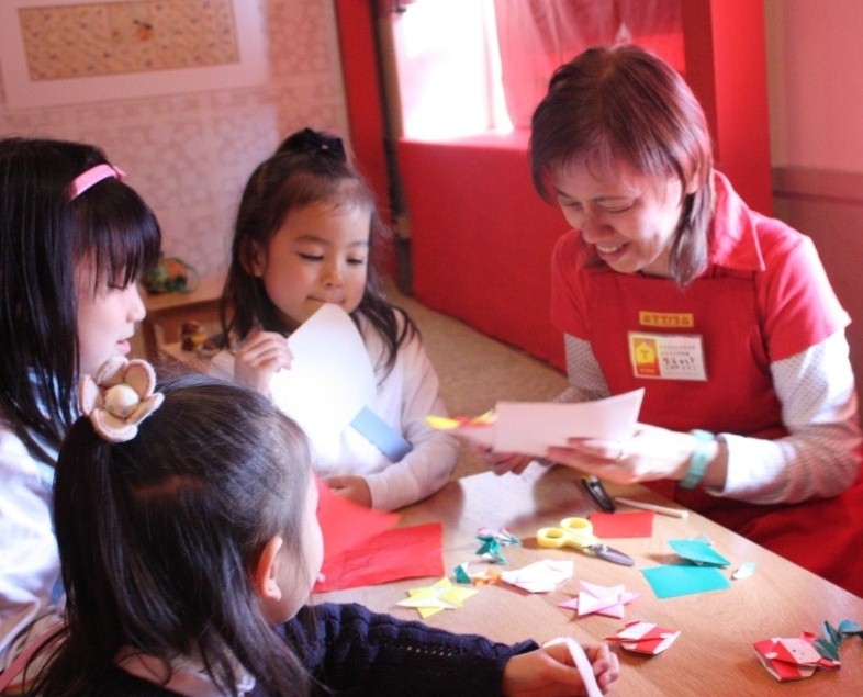 子供たちと学芸員が折り紙で遊んでいる様子