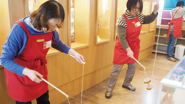 学芸員たちが木のヨーヨーで遊んでいる様子